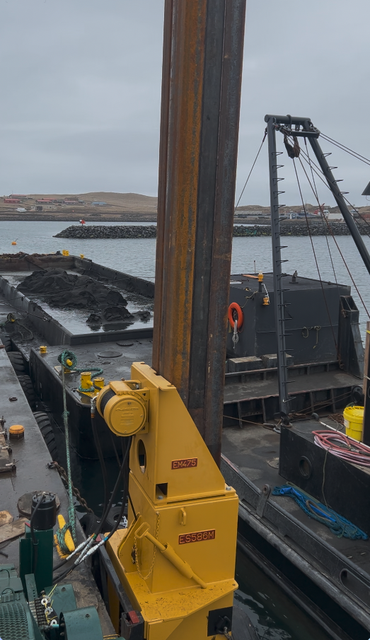 Hydraulic winch mounted alongside a steel pile on a barge